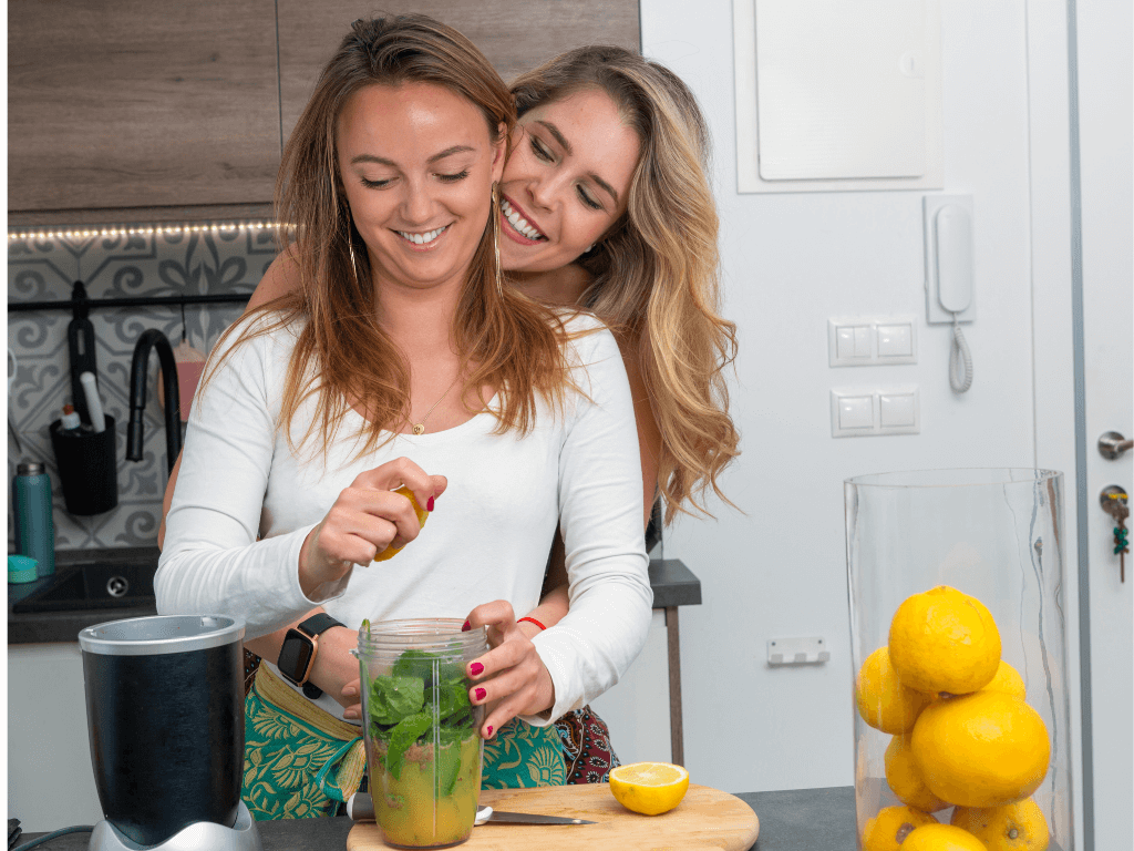 Two women having fun squeezing lemons for a smoothie.
